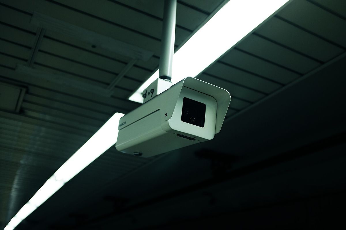 Una telecamera di sorveglianza appesa a un soffitto con luci al neon