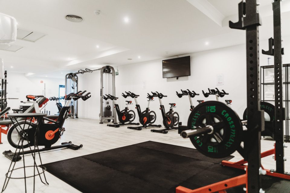 Una sala attrezzi vuota con macchine, bilancieri e bici da spinning