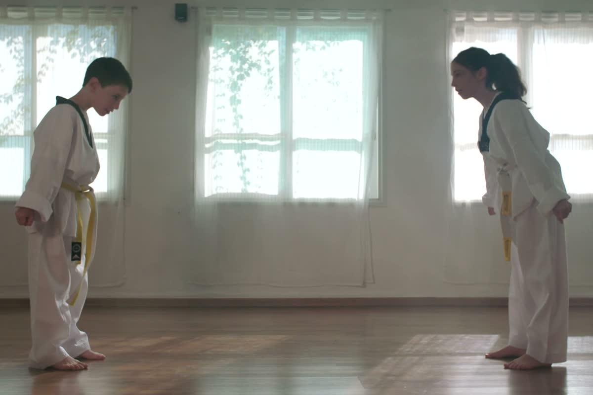 Due bambini in dobok bianco tirano un pugno in una sala di arti marziali
