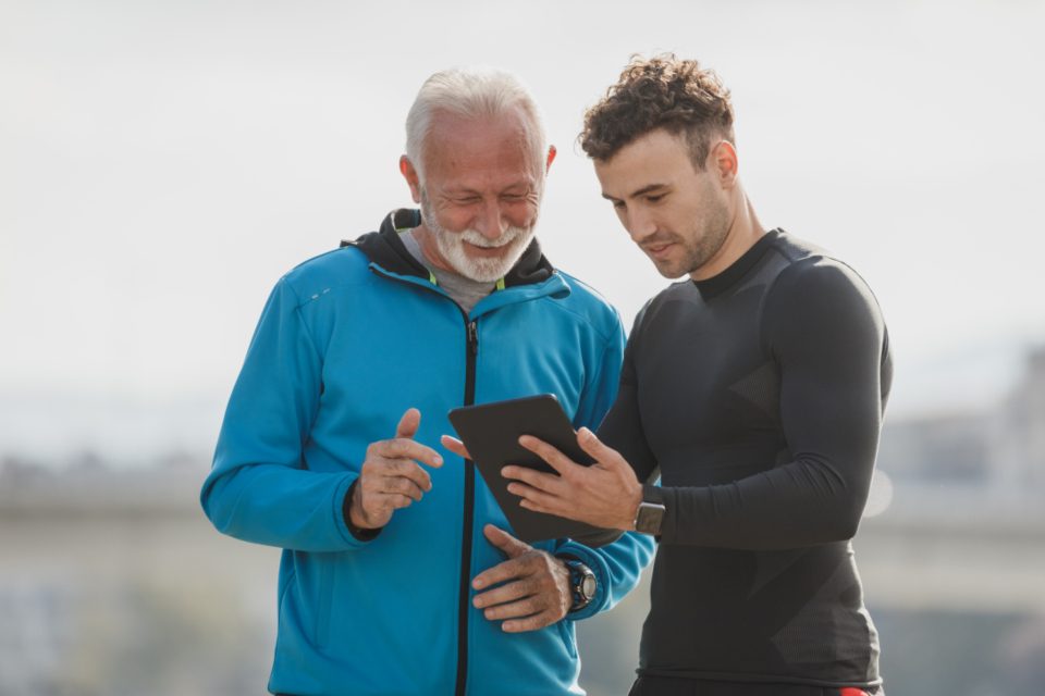Un personal trainer mostra il programma su un tablet a un cliente over 60