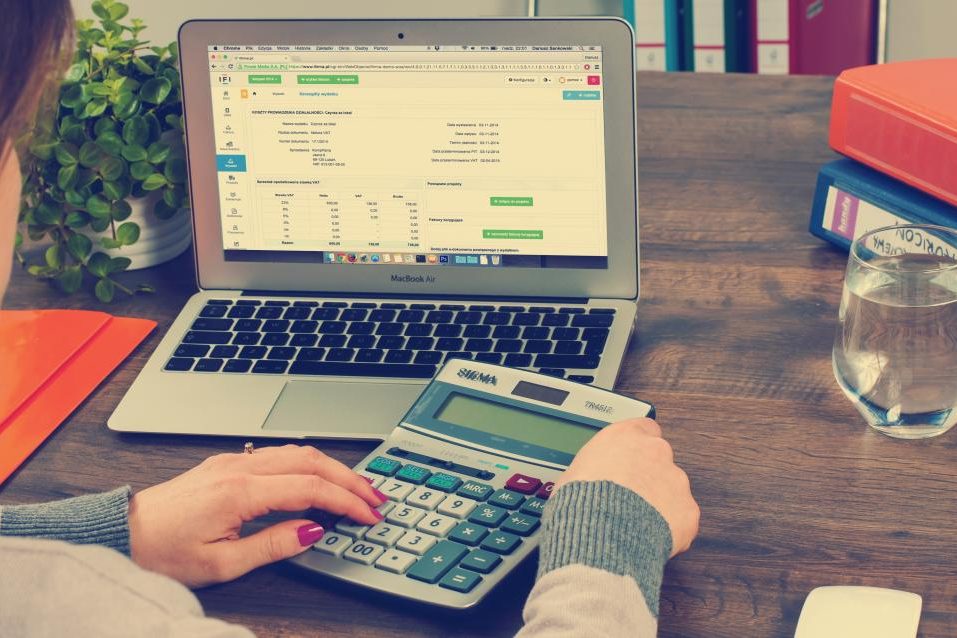 Mani che usano una calcolatrice accanto a un computer portatile