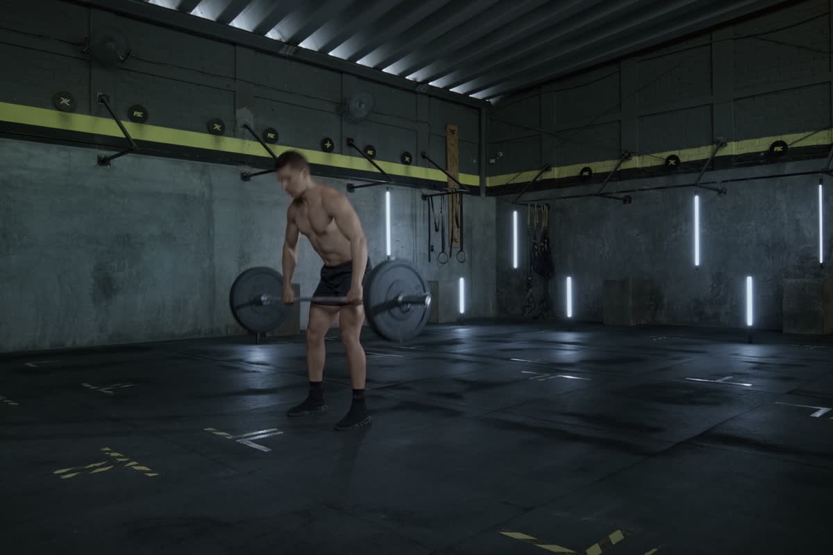 Un uomo solleva un bilanciere in una palestra industriale buia