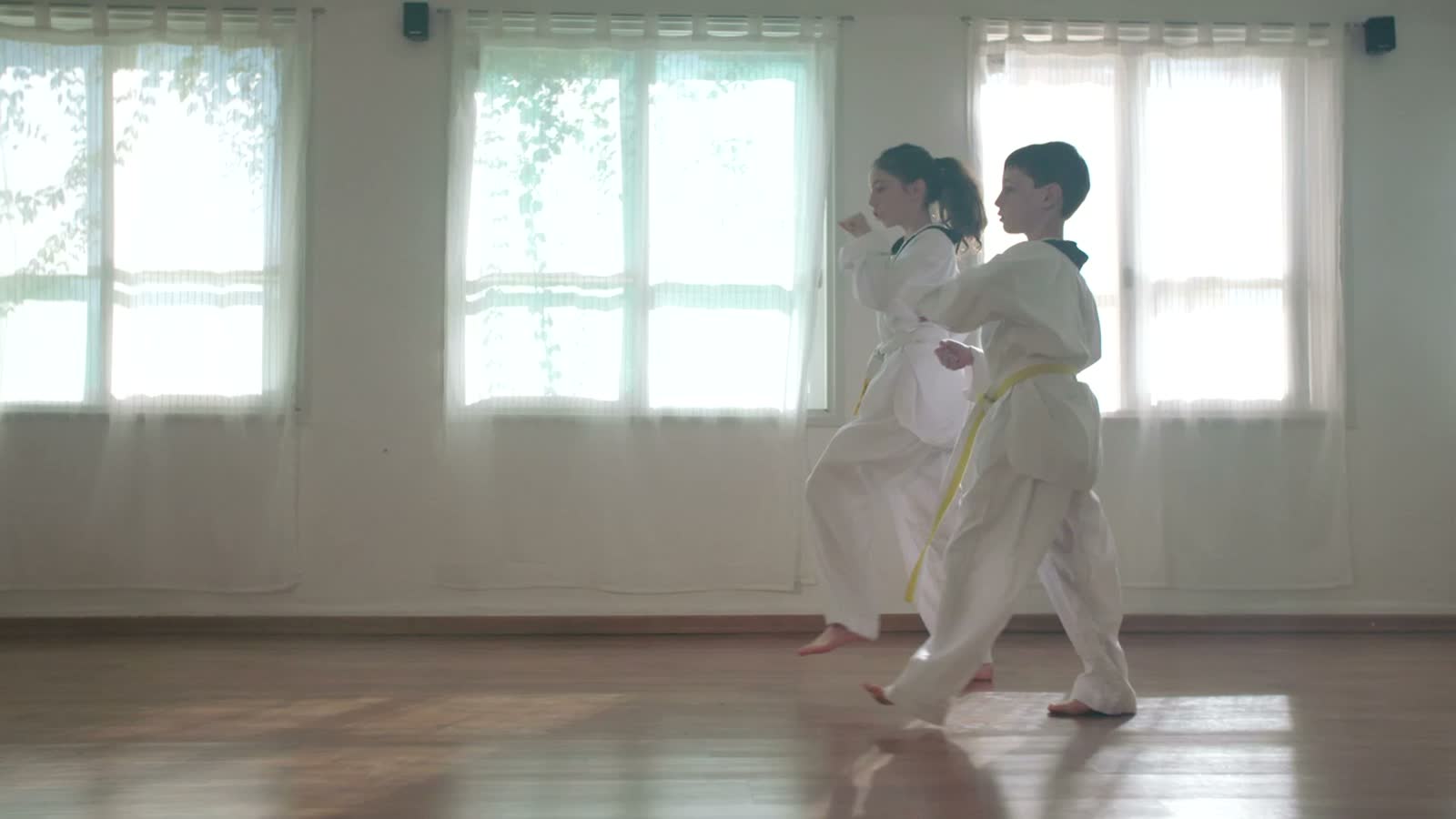 Due ragazzi in dobok bianco con la cintura gialla si allenano in una sala di arti marziali luminosa
