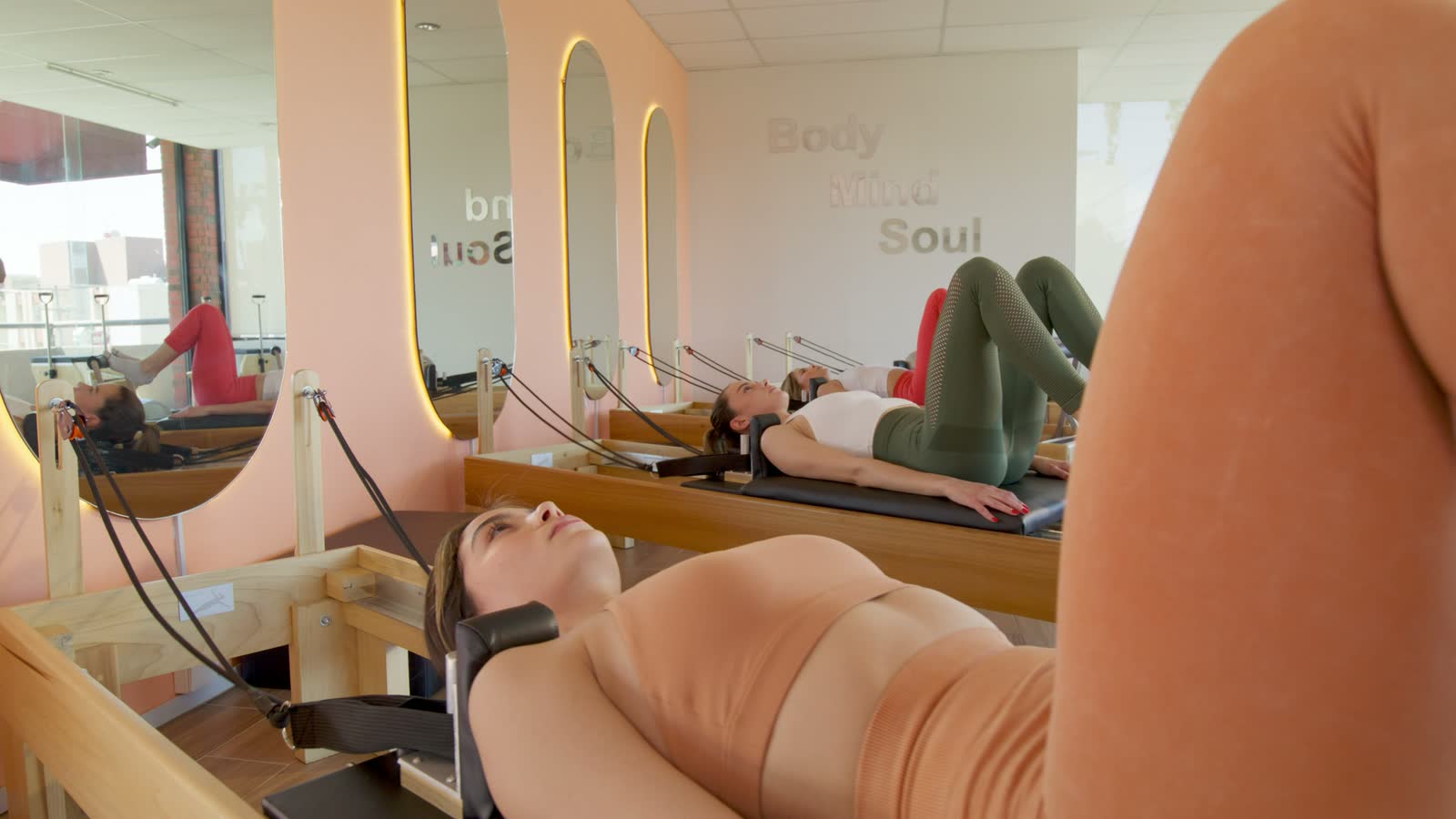 Una lezione di pilates reformer in uno studio luminoso con le pareti rosa